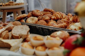 A variety of baked goods including bread, rolls, and pastries displayed in a basket. - Hotel Fontana (Novi Sad)