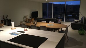 A modern dining area with a large table, chairs, and a sofa. There is a TV and a window with a view of the outside. - A Mont Nos Hôtes view of the Ventoux (Mollans-sur-Ouvèze)