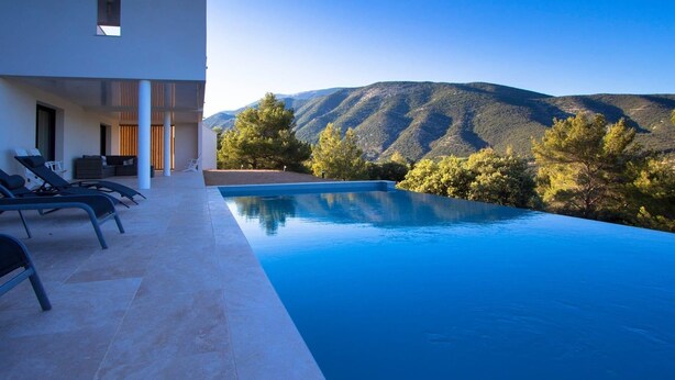 A modern infinity pool with a mountain view, sun loungers, and a minimalist outdoor seating area. - A Mont Nos Hôtes view of the Ventoux (Mollans-sur-Ouvèze)