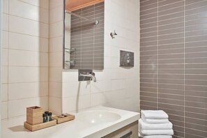A bathroom with a white sink, a mirror, a towel rack, and a shower. - Contemporary and comfortable apartment next to the Acropolis Museum (Athens)