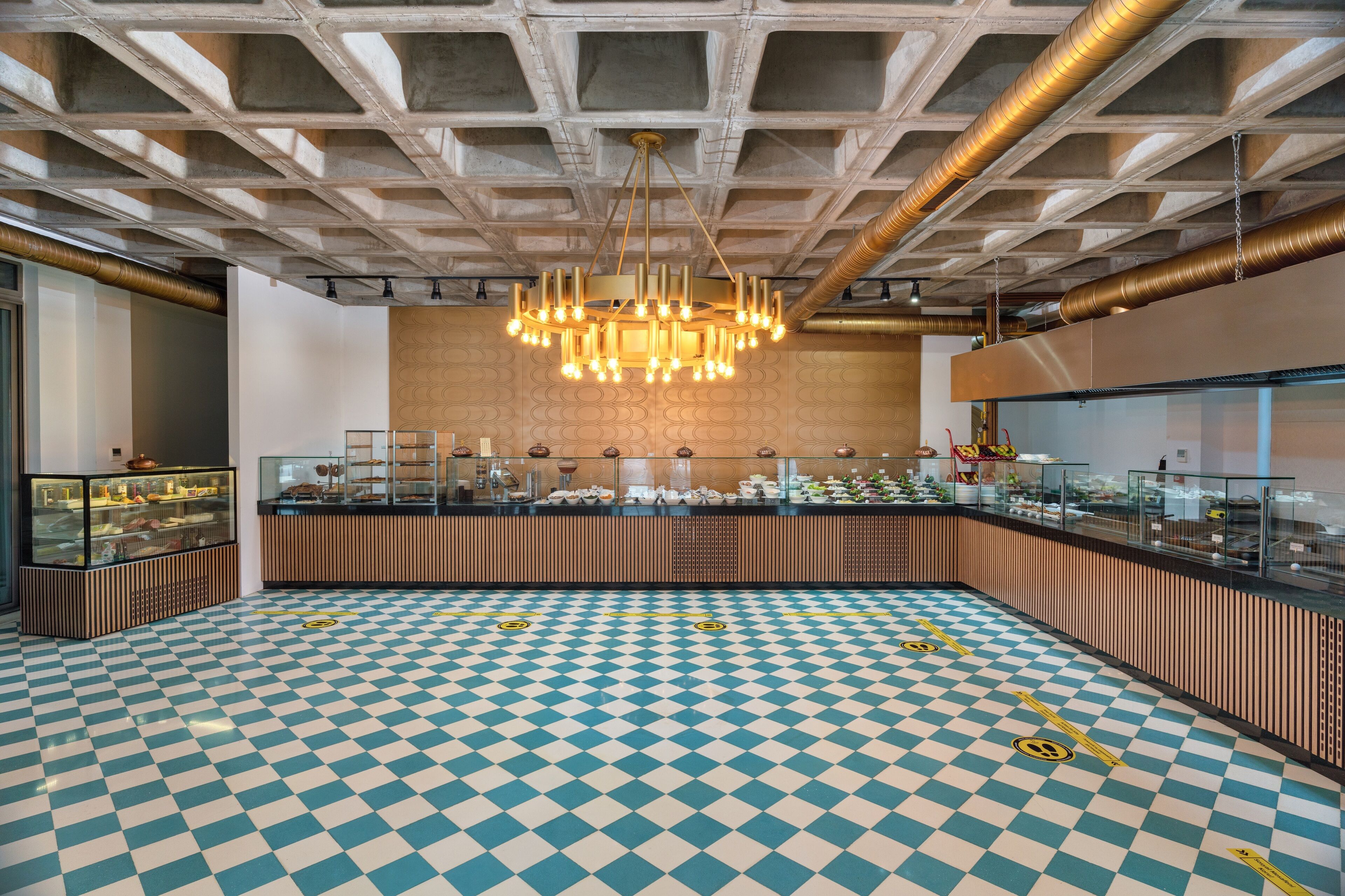 A spacious room with a checkered floor, a central chandelier, and a counter with various items displayed.