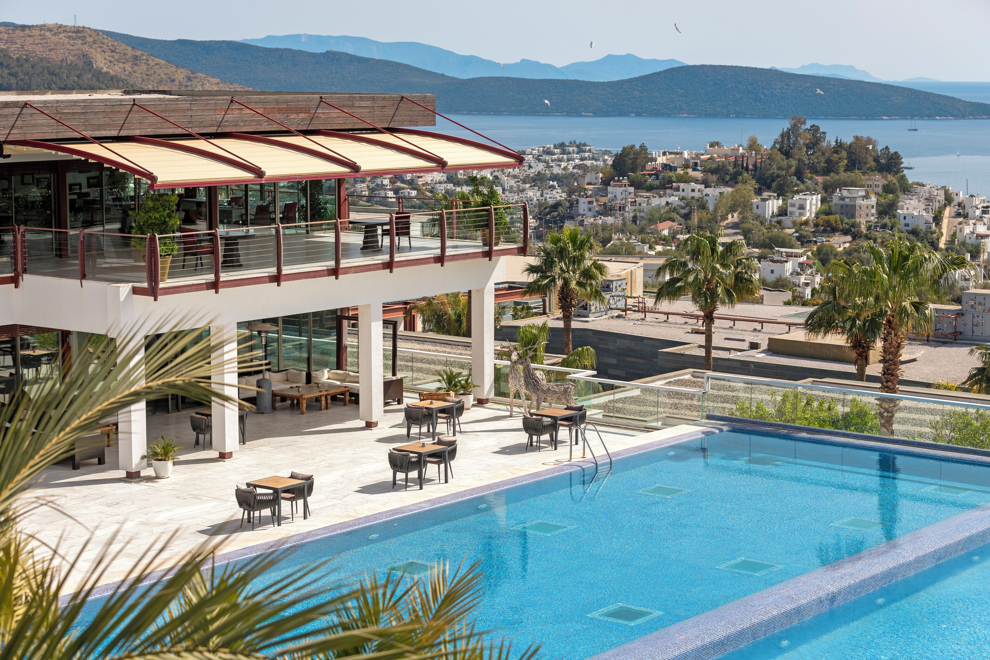 A rooftop pool with a view of a coastal town and mountains.