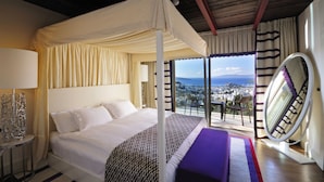 A bedroom with a canopy bed, a large window with a view of the city, and a circular mirror. - Hillstone Bodrum Hotel & Spa (Bodrum)