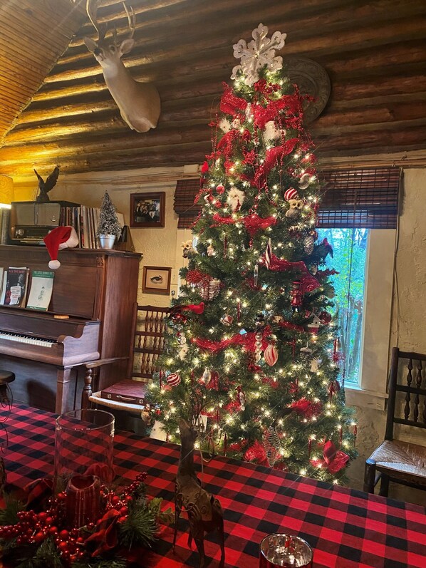Um quarto aconchegante com uma grande árvore de Natal, um piano e um chão xadrez.