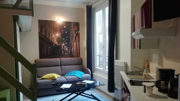 Un saló modern amb un sofà, una taula de centre i un mural de paisatge urbà a la paret.