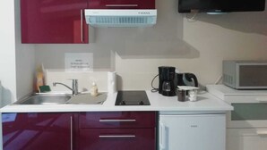Una cuina compacta amb microones, cafetera i nevera.