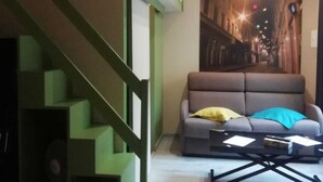 Un saló amb una escala verda, un sofà amb coixins i una taula de centre.