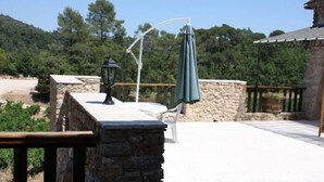 A stone patio with a table and chairs, a hanging umbrella, and a lantern. - Detached 2-bedroom apartment in charming building, swimming pool and terrace (Signes)