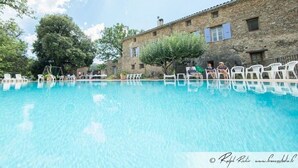 A swimming pool with white lounge chairs and a stone building in the background. - Detached 2-bedroom apartment in charming building, swimming pool and terrace (Signes)