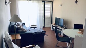 Olohuoneessa on sohva, nojatuoli, televisio ja ruokapöytä.