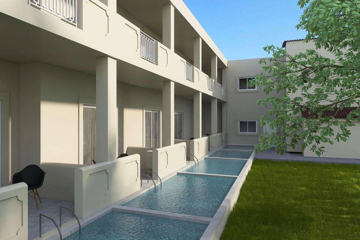 Een modern gebouw met een zwembad, balkons en een kleine tuin.