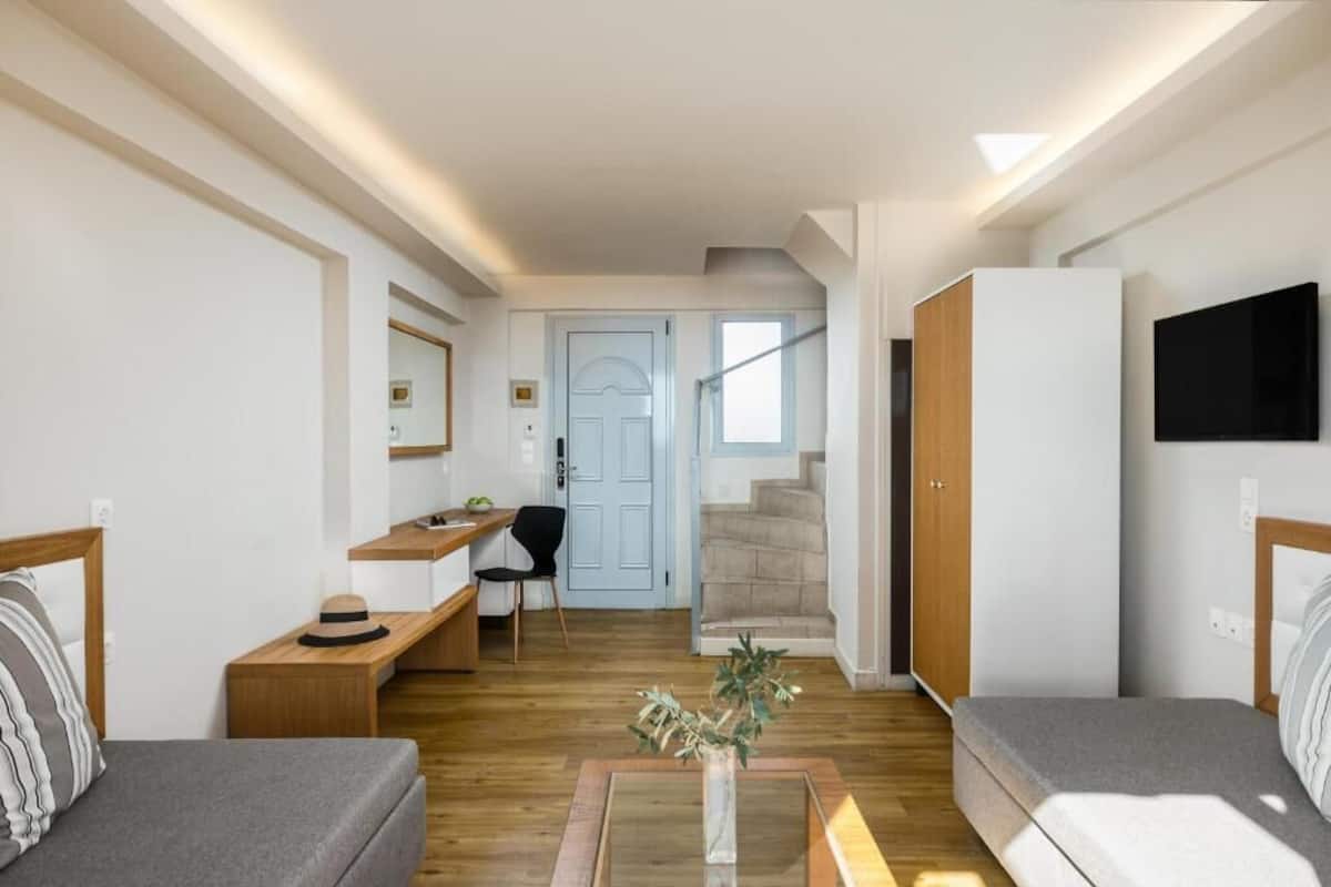 Een moderne woonkamer met een bank, een salontafel, een bureau en een aan de muur bevestigde televisie.