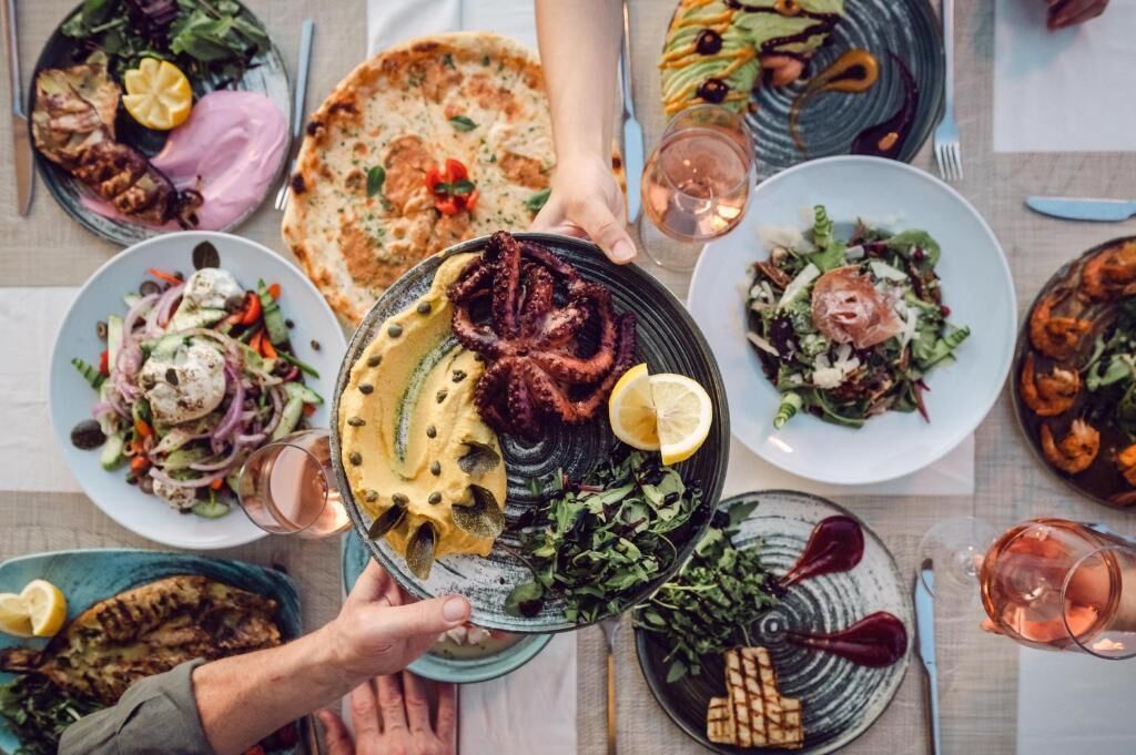 A dining table with various dishes, including grilled meat, salads, and flatbread.