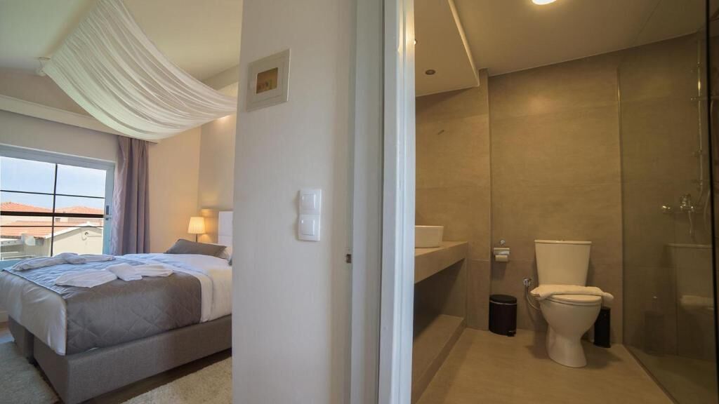 A modern hotel room with a large bed, a bathroom with a glass shower enclosure, and a view of the cityscape.