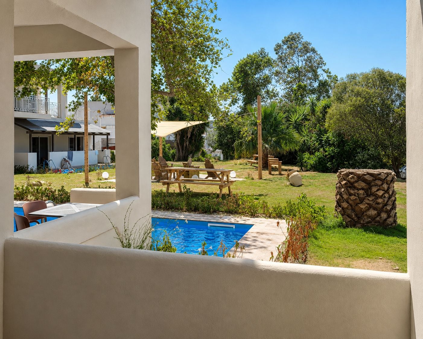 A pool area with a wooden deck, lounge chairs, and a stone wall.
