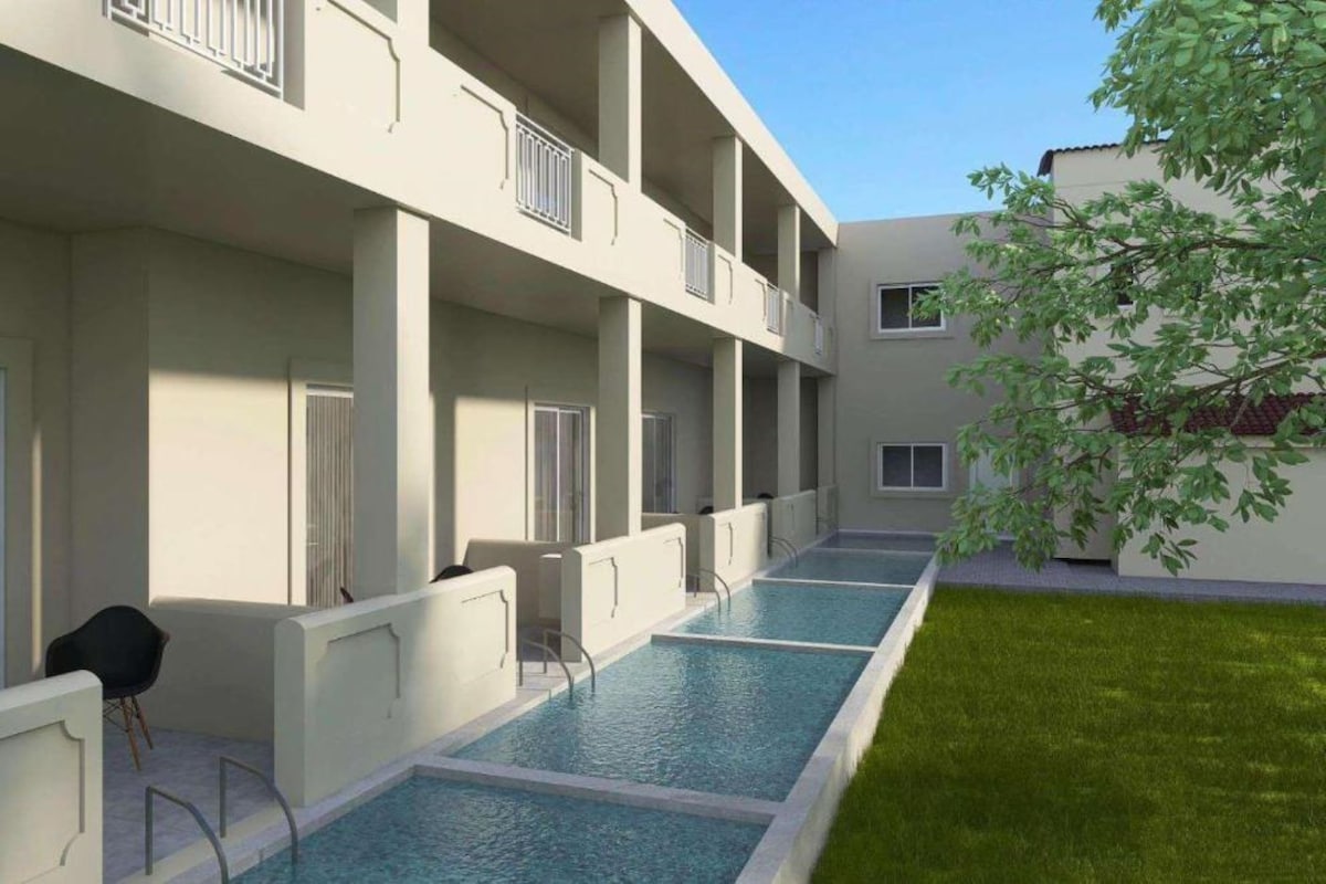 A modern building with a swimming pool, balconies, and a grassy area.
