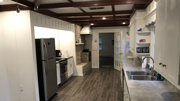 Una cocina moderna con armarios blancos, electrodomésticos de acero inoxidable y piso de madera.