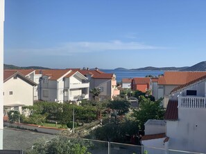 Uma área residencial costeira com casas de telhado em terracota, céu claro e vista para o mar.