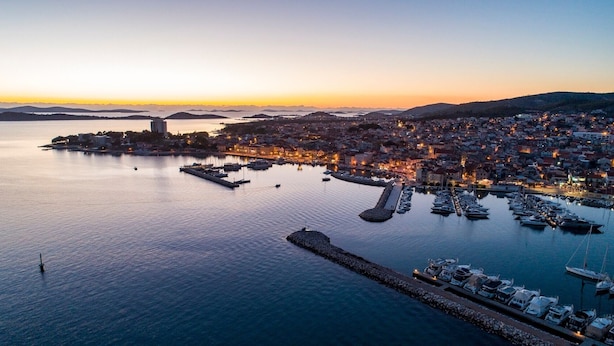 Un pueblo costero con un puerto deportivo, edificios y una vista despejada del agua.