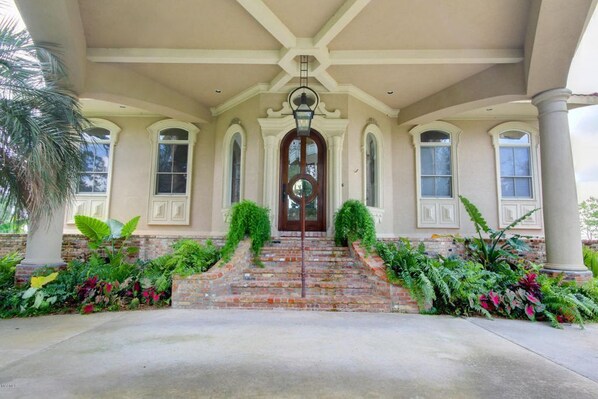 A grand entrance with a brick staircase, columns, and a large door.