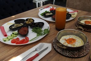 A wooden table with plates of food, including olives, tomatoes, and a bowl of eggs. - Ersoy Ikiz Otel (Antalya)