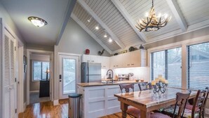 Una cocina moderna con armarios blancos, una mesa de comedor de madera y una araña.