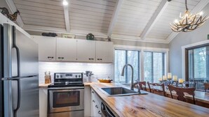 Una cocina moderna con electrodomésticos de acero inoxidable, una isla de madera y un comedor con candelabro.
