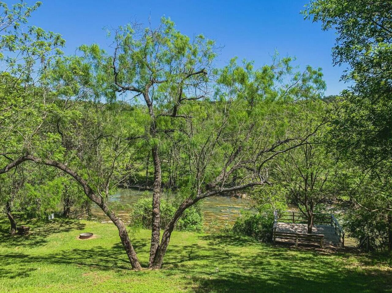 Un paysage naturel avec une rivière, des arbres et un banc.