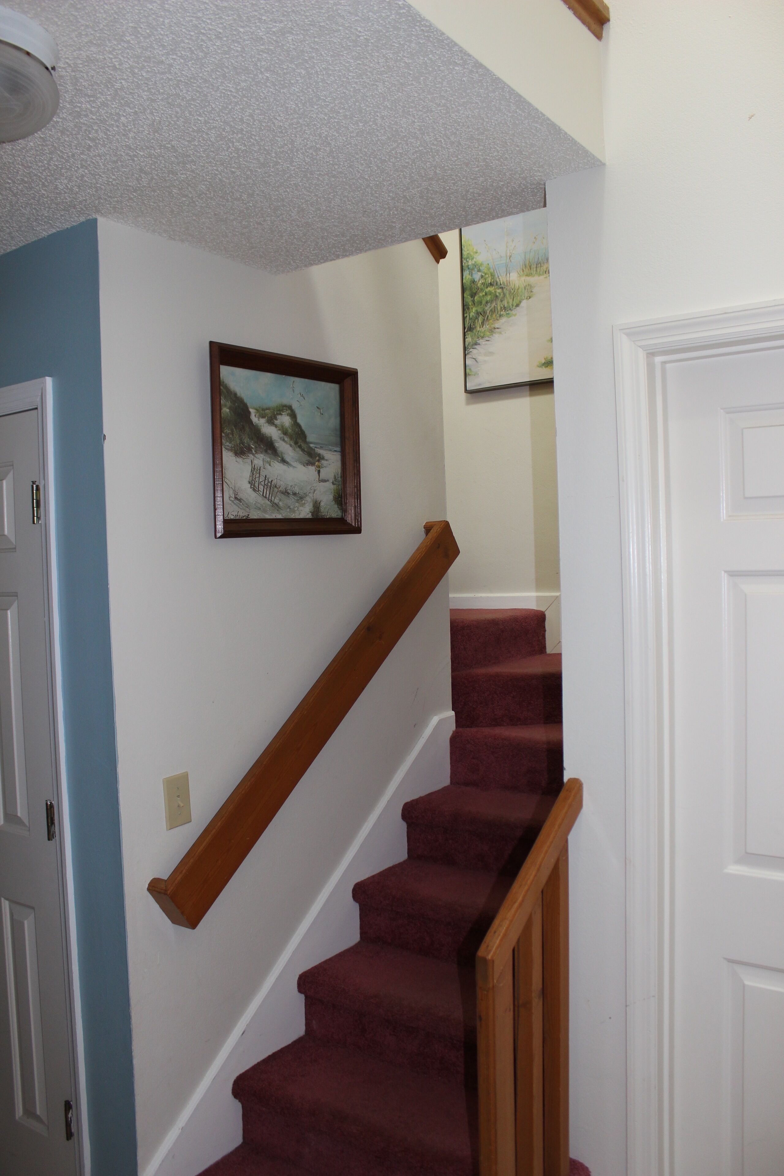 A staircase with wooden handrails and red carpeted steps leading to a landing.