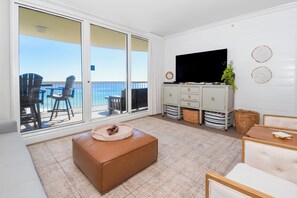 A living room with a large sliding glass door leading to a balcony with outdoor seating.