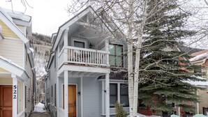 A two-story house with a balcony, a small porch, and a wooden door. - Bluebird Day (Telluride)
