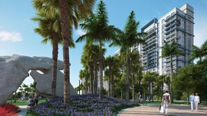 A modern building with balconies, surrounded by palm trees and a park with purple flowers. - Downtown Doral #504 - Studio - 5350 Park (Doral)
