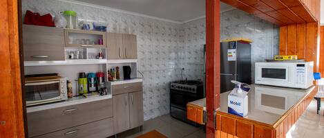 A modern kitchen with wooden cabinets, a microwave, a stove, and various kitchen appliances.