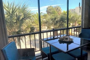 A balcony with a glass table and chairs, overlooking palm trees and a street. - Stylish Anglers Retreat Poolside and Ocean U16 (Marathon)