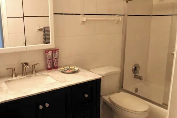 Une salle de bain équipée d  ’un lavabo, d’un miroir, de toilettes et d’une douche.