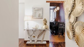 A dining area with a rustic wooden table, a Buddha statue, and a wall-mounted decorative piece. - LUXURY HISTORIC APARTMENT (Roma)