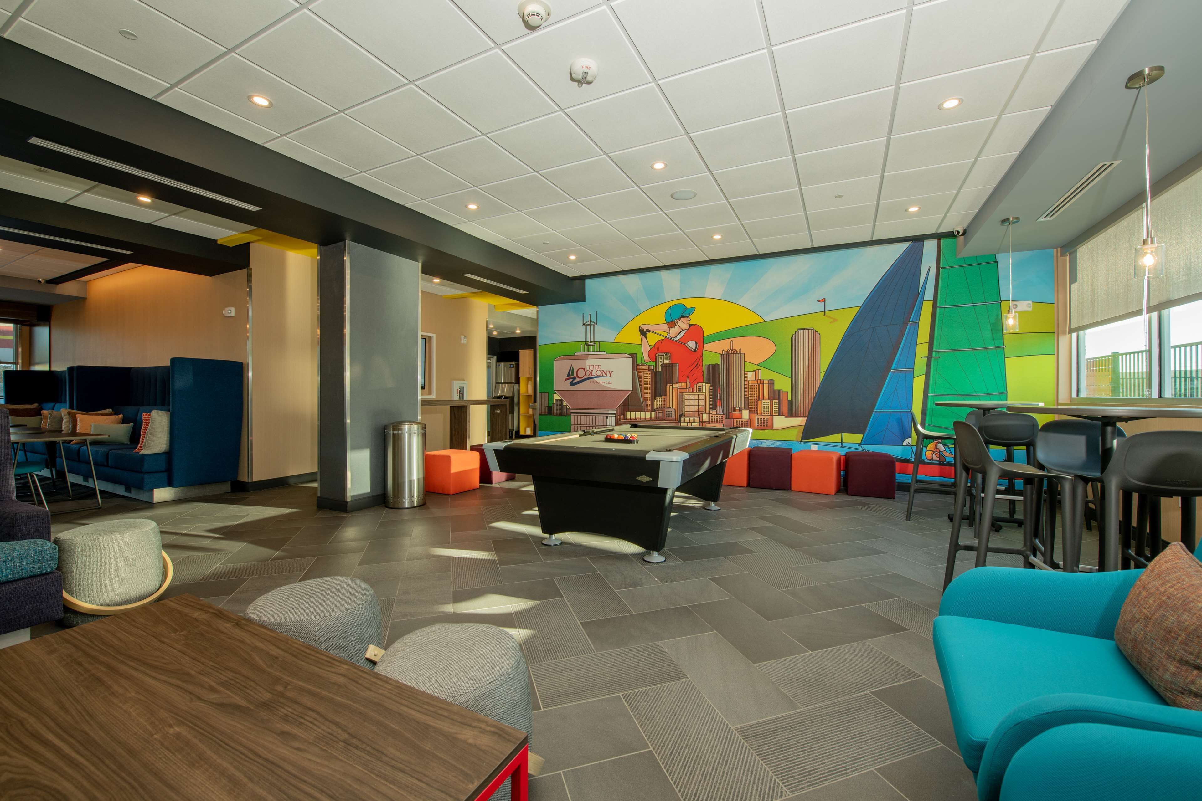 A modern lounge area with a pool table, comfortable seating, and a vibrant mural.