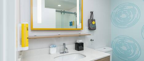 Et badeværelse med en hvid vask, et spejl med guldfarvet ramme, en håndklædeholder og et toilet.