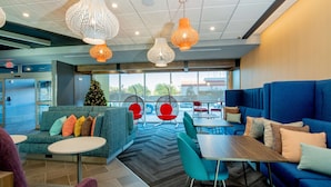 A modern hotel lobby with seating areas, a Christmas tree, and large windows. - Tru by Hilton The Colony Dallas (The Colony)