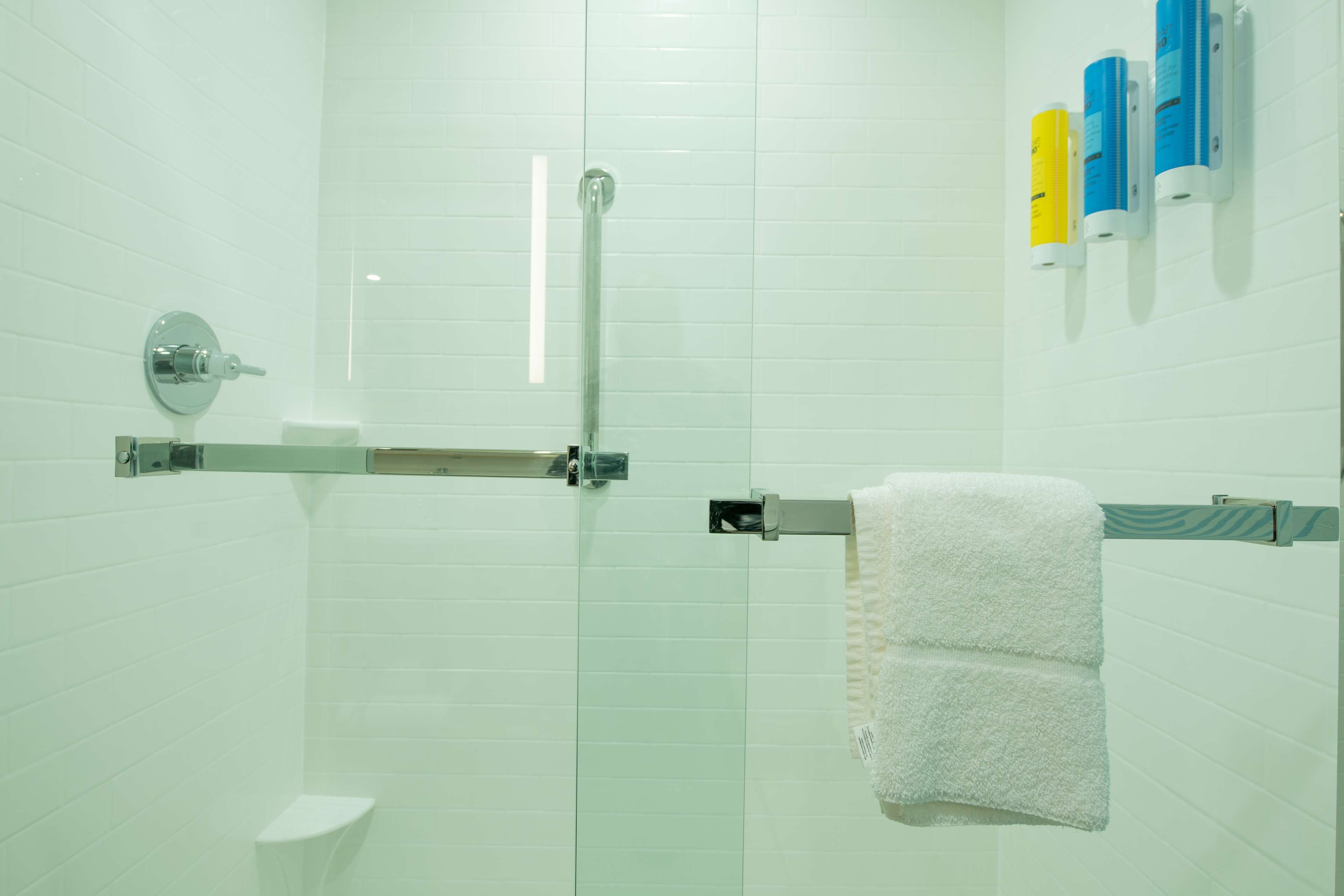Een moderne badkamer met een glazen douchecabine, een toilet en een handdoekrek met een witte handdoek.
