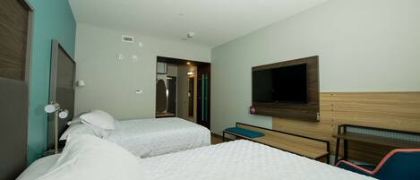 Una habitación de hotel con dos camas, un televisor en la pared, un escritorio y una silla.