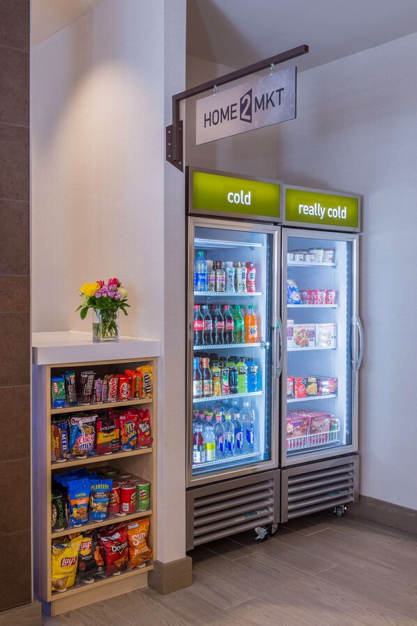 A vending machine area with snacks and a refrigerator labeled "HOME 2 MKT" with sections for "cold" and "really cold" beverages.