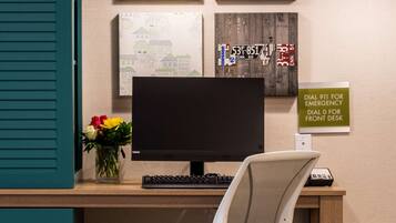 A modern office desk with a computer, a chair, and decorative wall art.