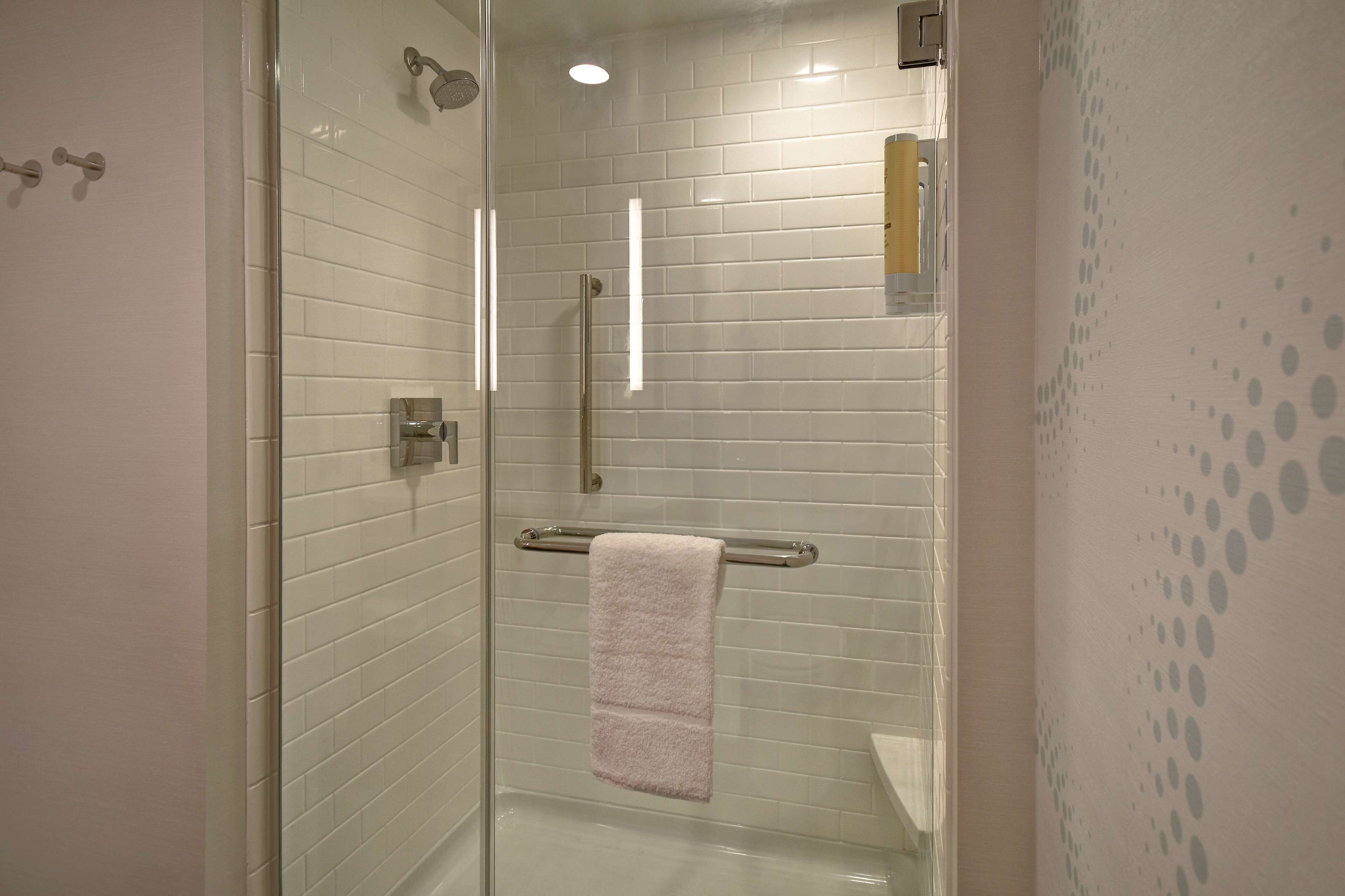 A glass-enclosed shower with white tiled walls, a visible towel rack, and a glass door.