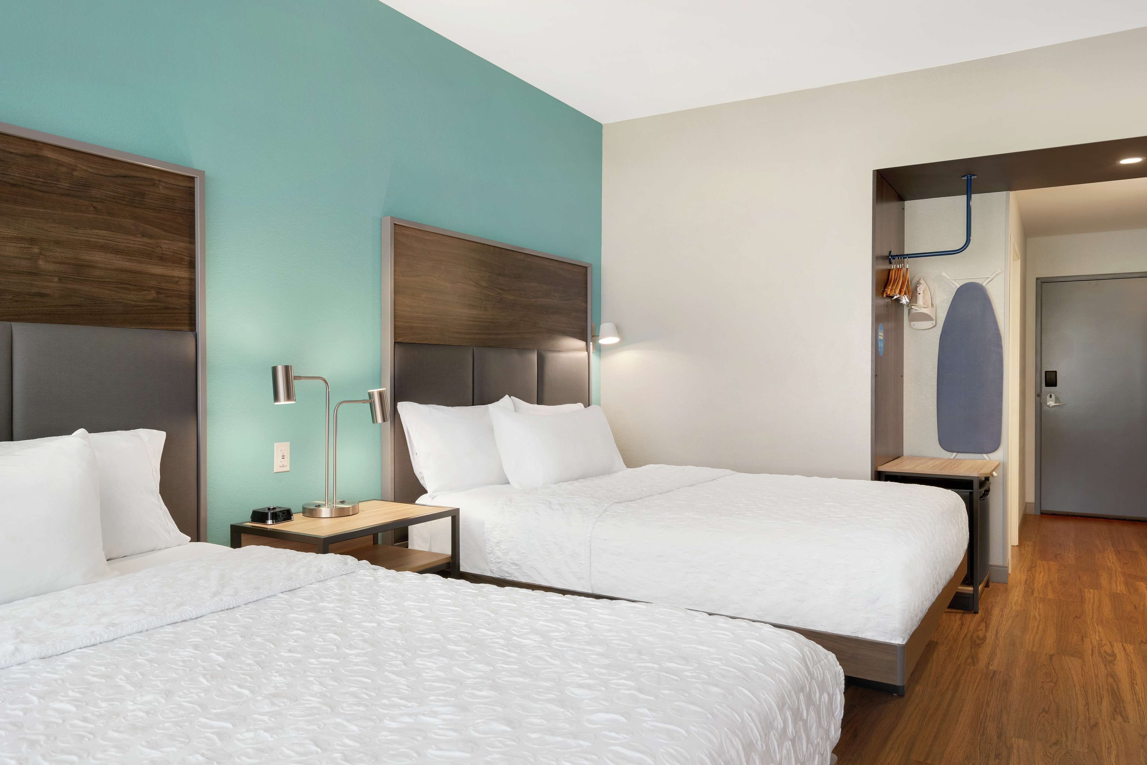 A hotel room with two beds, a desk, and a wardrobe.