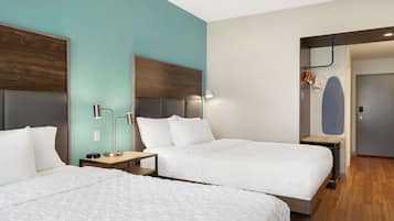 A hotel room with two beds, a desk, and a wardrobe.