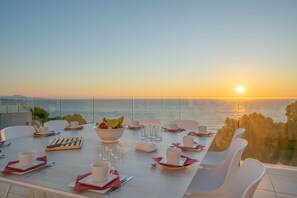 Een ontbijttafel met uitzicht op zee bij zonsondergang.