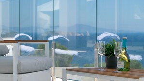 A balcony with a table, two wine glasses, a bottle of wine, and a potted plant. - Casa Emnitan - Begur (Begur)