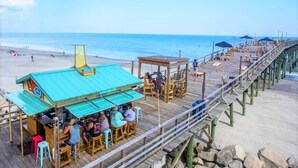 Um cais com restaurante e área de estar com vista para a praia.