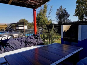 Relax by the pool under a shaded pergola with a comfortable bench and table.